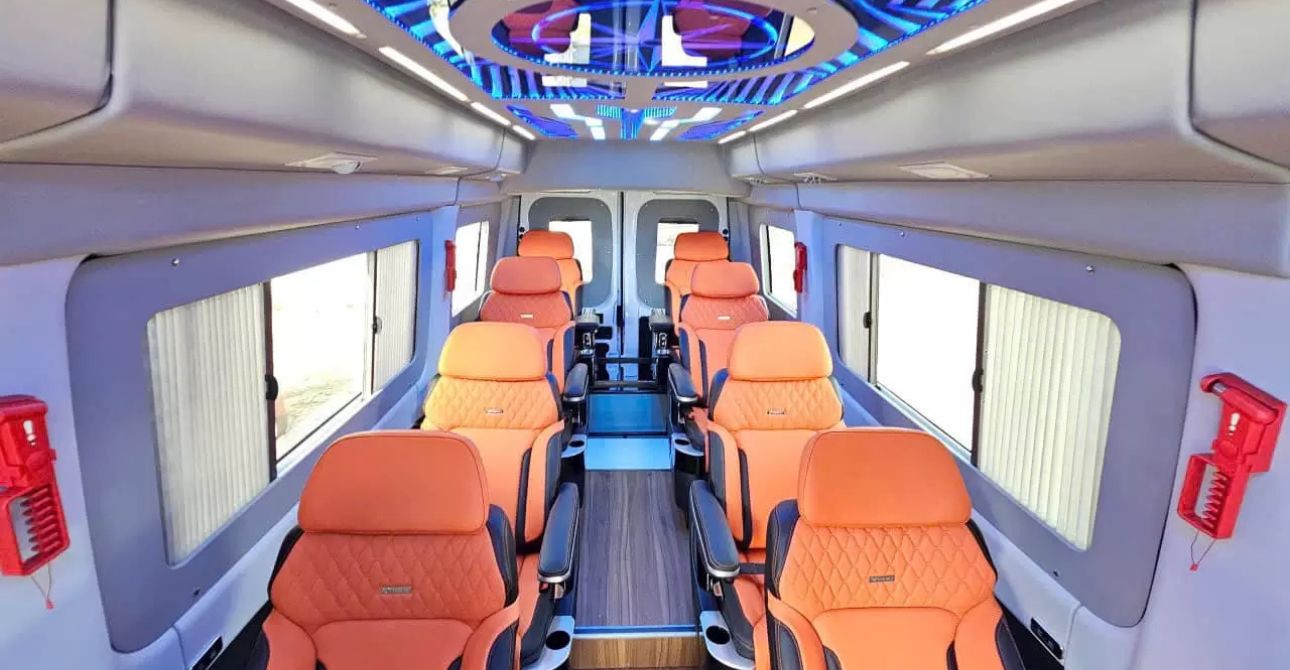 Interior of EcoSapa VIP limousine bus — reclining individual seats with leg rests, USB charging, and mountain views through windows