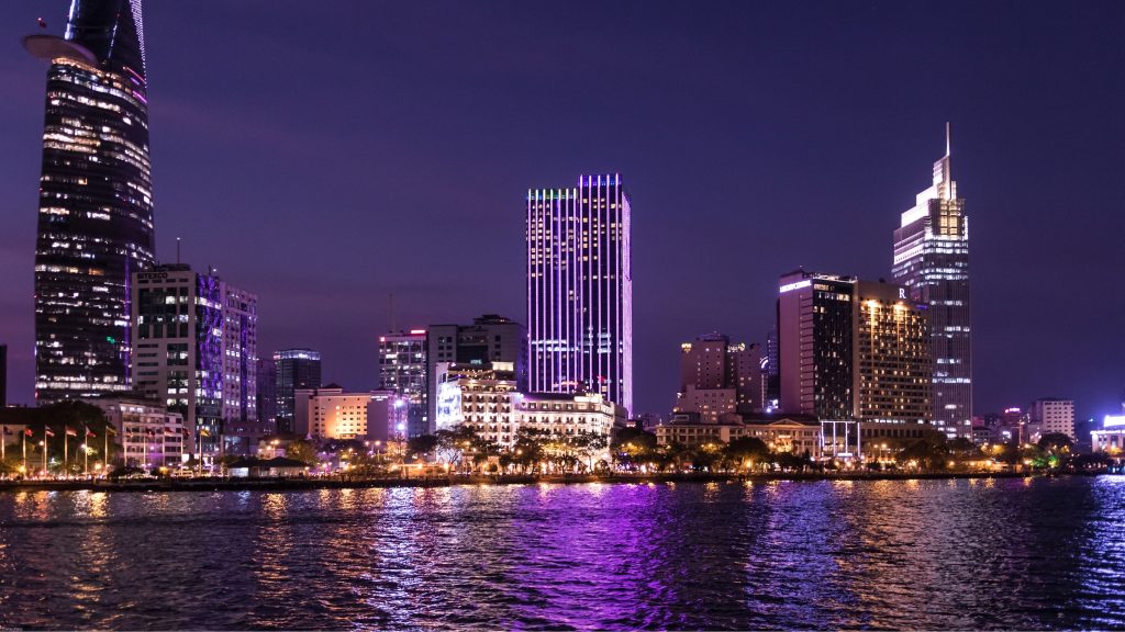 Cross Over The Saigon River As The Skyline Glows Gold Against The Evening Sky